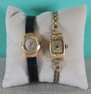 pair of ladies ' s wrist watches on a cushion with a pillow
