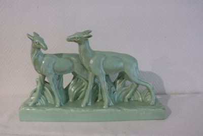 a green statue of two deer and a doe in the grass