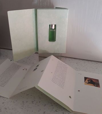 trois livres ouverts posés sur un comptoir, à côté d'un flacon de parfum
