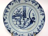 a blue and white plate with a bird and a birdcage on it