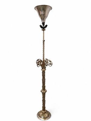 un lampadaire ancien en laiton surmonté d'un abat-jour en verre