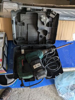 une boîte contenant une perceuse et d'autres outils, posée par terre