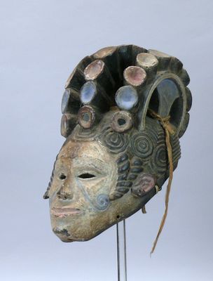 une image représentant un masque en bois posé sur un socle en métal