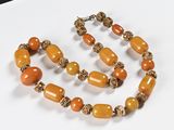 a close up of a necklace with orange beads on a white surface