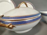 a white bowl with a gold handle and a blue and white bowl with a gold handle
