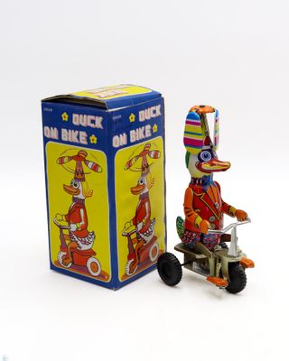 figurine représentant un clown sur un tricycle, à côté d'une boîte