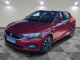une voiture rouge est garée dans une pièce au sol en damier
