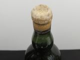 une petite bouteille bouchée d'un bouchon en liège, posée sur une surface noire