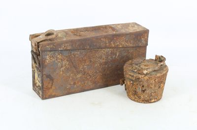 une vieille boîte rouillée et une tasse posées sur une surface blanche