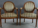 deux chaises avec des accoudoirs rembourrés à rayures et des pieds en bois