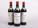 trois bouteilles de vin rouge sont posées côte à côte sur une surface blanche
