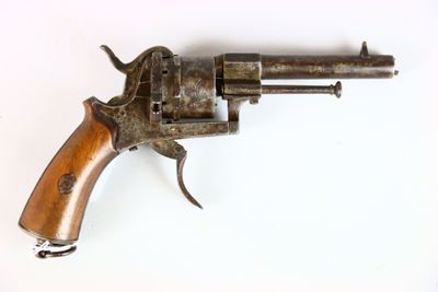 un vieux pistolet avec une poignée en bois sur une surface blanche