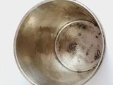 a silver bowl with a spoon in it on a white surface