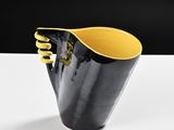 yellow and black vase on a white table with a black background