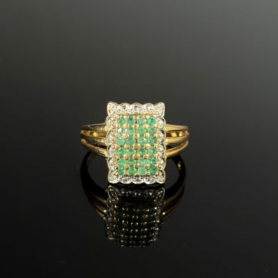 une bague en émeraude et diamant sur une surface noire