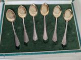 five spoons in a box on a green surface