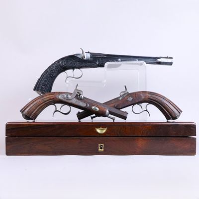 Deux armes à feu sont exposées dans une vitrine en bois sur fond blanc.