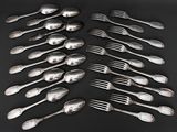a lot of silver spoons and forks on a black table