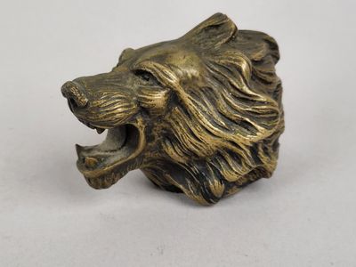 figurine en laiton représentant une tête de lion à la gueule ouverte sur fond blanc