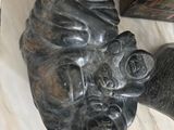 a statue of a head on a table with a person standing next to it