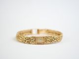 a close up of a gold bracelet on a white surface