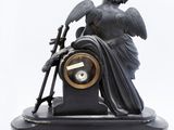 a statue of an angel holding a clock on a stand