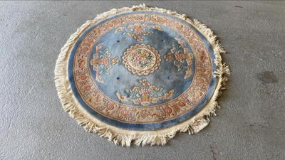 un tapis rond posé à même le sol, orné de franges