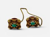 une paire de boucles d'oreilles en or ornées de pierres vertes sur fond blanc