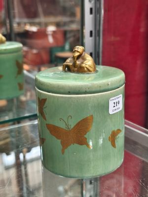 un récipient vert orné d'un motif de papillon doré