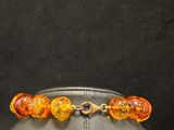 a close up of a bracelet with orange beads on a mannequin head