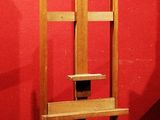 une chaise en bois posée sur un socle, adossée à un mur rouge