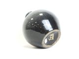 a close up of a black ball on a white surface