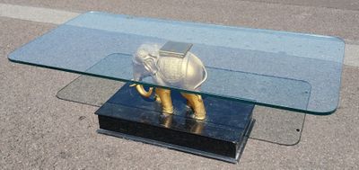 une table basse en verre sur laquelle trône un éléphant doré