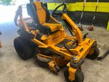 une tondeuse autoportée jaune dans un garage, avec des outils posés par terre