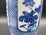 blue and white vase with a rope wrapped around it on a table