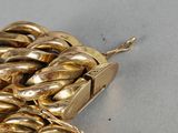 a close up of a gold chain bracelet on a white surface
