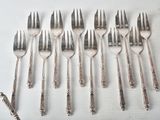 six forks and six spoons are lined up on a white surface