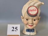 a small statue of a boy with a bottle cap on his head