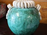 un vase vert contenant des coquillages blancs, posé sur une table