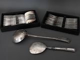 plusieurs cuillères en argent et un repose-cuillère dans une boîte posée sur une table