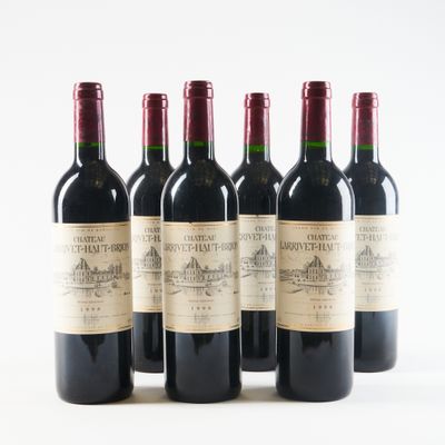 six bottles of wine are lined up in a row on a white surface