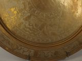 a gold plate on a wall with a clock on it