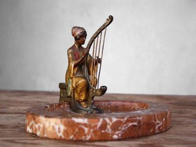 une statue représentant une femme jouant de la harpe, posée sur un socle en marbre