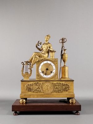 a gold clock with a statue of a woman sitting on top of it