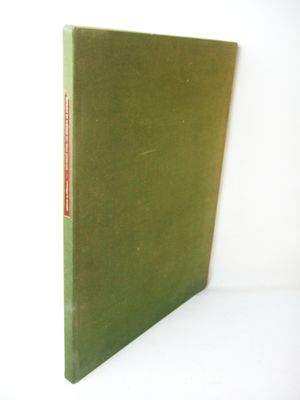 an old book with a green cover sitting on top of a white table