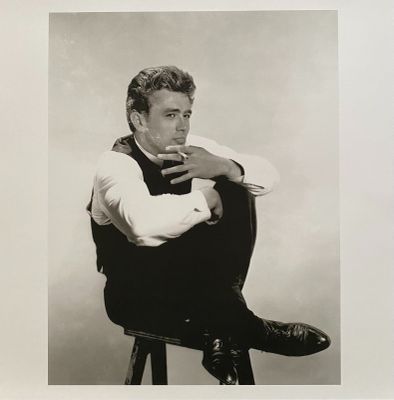 black and white photograph of a man sitting on a stool with his hand on his chin