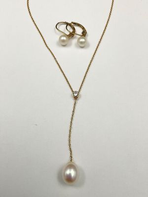 a gold necklace and earring set with pearls on a white background