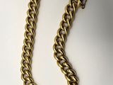 gros plan d'un collier à chaîne en or sur une surface blanche