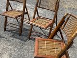 three wooden chairs sitting on top of a gravel road next to a field