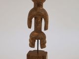 une image représentant une statue en bois d'un homme posée sur un bloc de bois